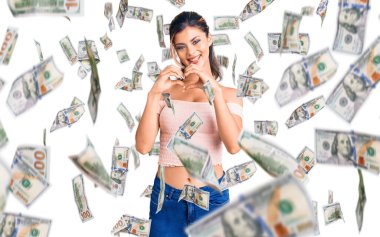 Genç ve güzel bir kadın, gündelik kıyafetler giyip, aşıkken gülümsüyor ve elleriyle kalp sembolü yapıyor. romantik kavram.