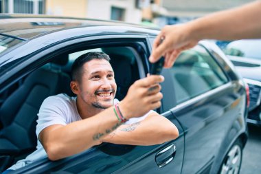 Yeni arabanın anahtarını tutarken mutlu gülümseyen İspanyol genç adam.