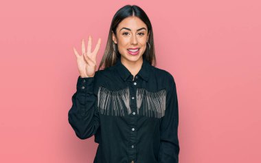 Genç İspanyol kadın gündelik giysiler giyer ve parmaklarını dört numarayı göstererek gülümserken kendinden emin ve mutlu.. 