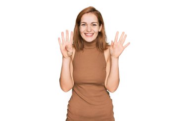 Gündelik giysiler giyen genç beyaz kadın dokuz numarayı gösterip işaret ederken kendinden emin ve mutlu bir şekilde gülümsüyor.. 