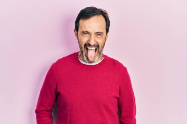 Orta yaşlı İspanyol bir adam günlük kıyafetler giyip komik bir ifadeyle dilini dışarı çıkarıyor. duygu kavramı. 