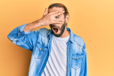 Uzun saçlı ve sakallı çekici bir adam. Sıradan bir kot ceket giyiyor. Şok içinde yüzünü ve gözlerini eliyle kapatıyor. 