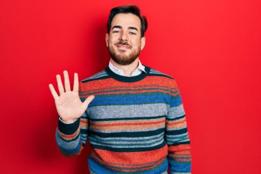 Sakallı, zarif yün süveter giyen yakışıklı beyaz adam beş numarayı gösteriyor ve gülümsüyor.. 