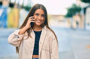 Genç İspanyol kız gülümsüyor. Şehirdeki akıllı telefondan konuşuyor..