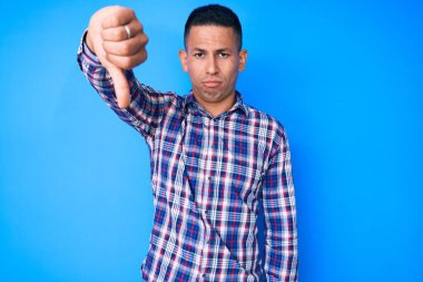 Genç, yakışıklı, gündelik kıyafetler giyen, mutsuz görünen, reddedilmiş ve olumsuz davranan Latin bir adam. kötü ifade. 