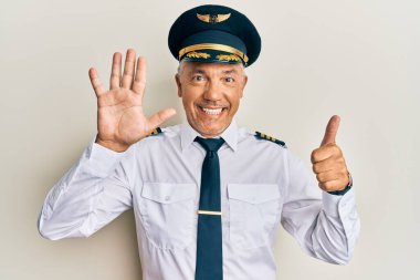 Yakışıklı, olgun, uçak pilotu üniforması giyen altı numaralı parmaklarıyla gülümseyerek kendinden emin ve mutlu bir şekilde onu işaret eden.. 