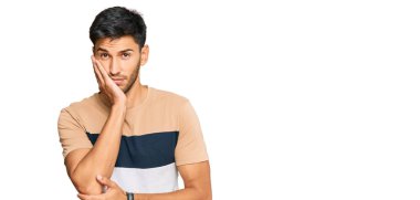 Gündelik kıyafetler giyen yakışıklı genç adam kollarını kavuşturarak depresyondan sıkılmış ve yorgun görünüyor.. 