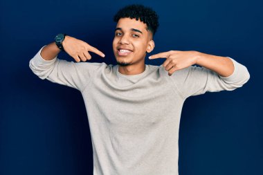 Gündelik kıyafetler giyen, neşeli gülümseyen, parmaklarıyla ve ağzıyla işaret eden Afrikalı genç bir Amerikalı. diş sağlığı kavramı. 