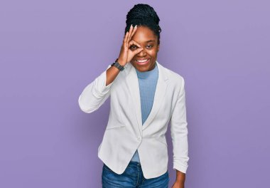 Genç Afro-Amerikan kadın iş kıyafetleri giyiyor. El hareketleriyle gülümsüyor, gözleriyle gülen parmaklarının arasından bakıyor.. 