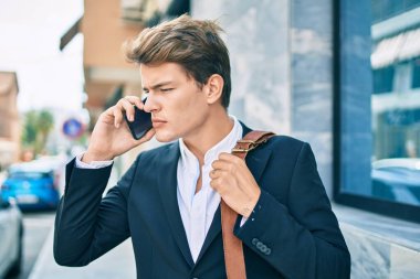 Kafkasyalı genç iş adamı ciddi bir ifadeyle şehirdeki akıllı telefondan konuşuyor..