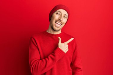 Sakallı, yün kazaklı, kışlık şapkalı, neşeli, eli ve parmağı yanda olan kel bir adam. 