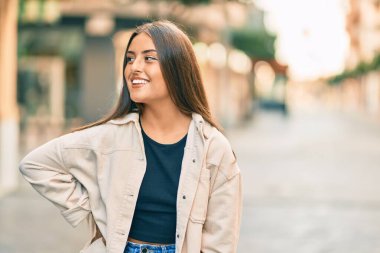 Genç İspanyol kız gülümseyerek şehirde mutlu mesut dikiliyor..