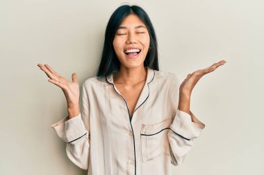 Pijama giymiş genç Çinli bir kadın başarının çılgınlığını kutluyor. Kollarını kaldırmış, gözlerini kapatmış heyecanlı çığlıklar atıyor. Kazanan konsept 