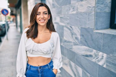 Genç İspanyol kadın gülümseyerek şehirde mutlu mesut yürüyor..