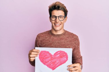 Yüzünde mutlu ve havalı bir gülümsemeyle gülümseyen kalbi olan yakışıklı beyaz bir adam. diş gösterme. 