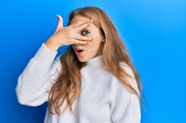 Sarışın, beyaz, sıradan bir kazak giyen güzel bir kadın. Şoka girmiş, yüzünü ve gözlerini eliyle kapatmış, parmaklarından korkuyla bakıyor. 