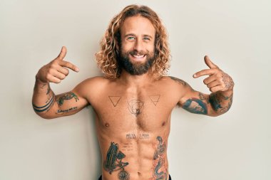 Sakallı, uzun saçlı, gömleksiz, kendine güvenen, gülümseyen, kendini gururlu ve mutlu gösteren bir adam.. 