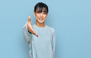 Genç İspanyol kadın günlük kıyafetler giyip gülümseyerek selamlaşma ve dostça tokalaşma sunuyor. başarılı iş. 