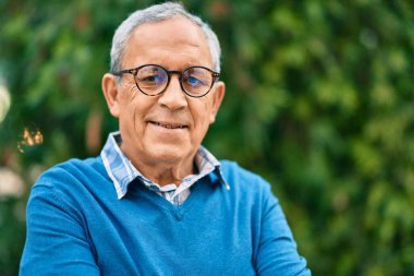 Yaşlı, kır saçlı, gülümseyen adam şehirde mutlu bir şekilde duruyor..