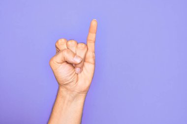 İzole edilmiş mor arka planda parmaklarını gösteren beyaz bir gencin eli serçe parmağının söz verme sözü olduğunu gösteriyor. Bir numara: