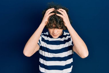 Yakışıklı, çizgili tişört giyen, baş ağrısı çeken çaresiz ve stresli bir genç adam. Çünkü acı ve migren ağrısı var. Eller başının üstünde.. 