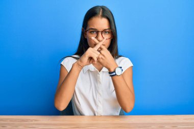 Güzel İspanyol kadın, gündelik giysiler içinde masada oturuyor. Reddedilmiş yüz ifadesi, negatif işaret veriyor. 