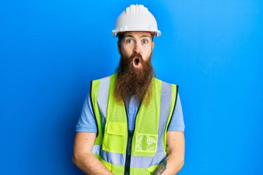 Uzun sakallı, güvenlik kaskı takan, parlak ceketli, korkmuş ve şok olmuş kızıl saçlı bir adam.. 
