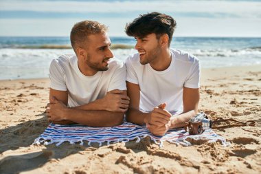 Genç eşcinsel çift kumsalda mutlu bir şekilde yatıyor..