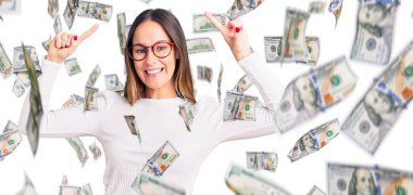 Güzel esmer, beyaz süveter giyen ve gözlüklü genç bir kadın. Şaşırmış, şaşırmış, parmaklarıyla işaret ediyor ve kollarını kaldırıyordu..