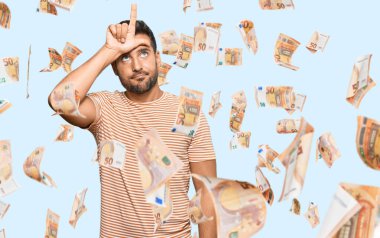 Yakışıklı İspanyol adam gündelik kıyafetler giyiyor. Alnında parmakları olan insanlarla dalga geçiyor. Ezik hareketler yapıyor, alay ediyor..