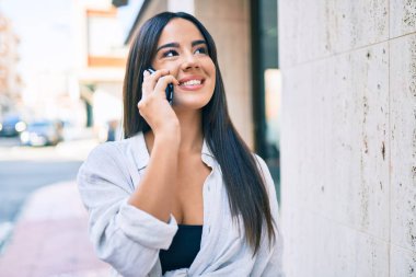 Genç İspanyol kız gülümsüyor. Şehirdeki akıllı telefondan konuşuyor..