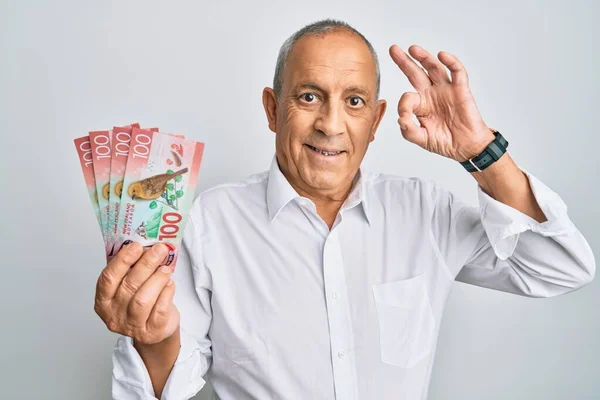 Handsome Senior Man Holding 100 New Zealand Dollars Banknote Doing — Stock Photo, Image