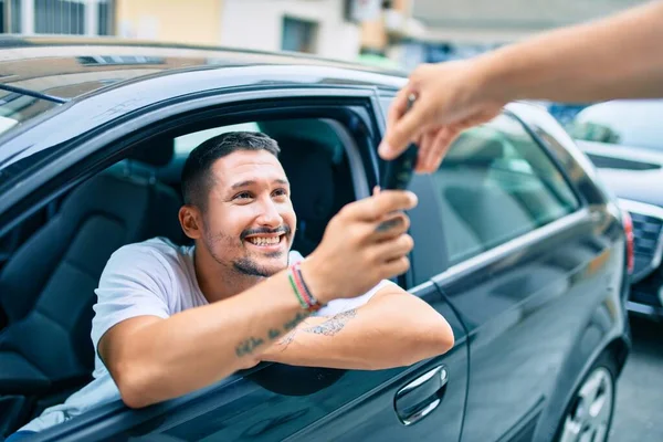 Yeni arabanın anahtarını tutarken mutlu gülümseyen İspanyol genç adam.