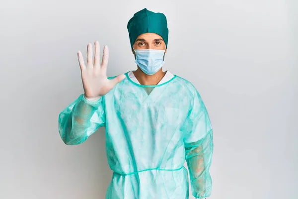 Fiatal Jóképű Férfi Sebész Egyenruhában Orvosi Maszkban Ötös Számú Ujjal — Stock Fotó