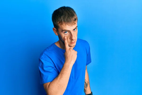 年轻的高加索男人穿着休闲的蓝色T恤 指着你的眼睛看着你的动作 可疑的表情 — 图库照片