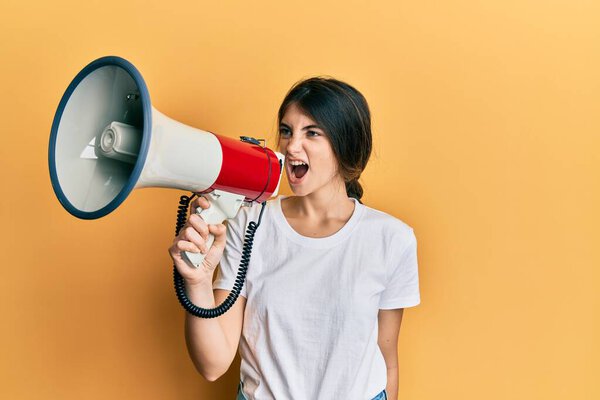 молодая азиатка с мегафоном на желтом фоне