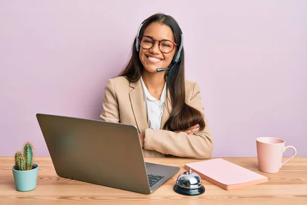 Beautiful hispanic woman working at the office wearing operator headset happy face smiling with crossed arms looking at the camera. positive person.