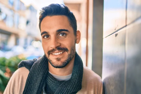 Joven Hombre Hispano Sonriendo Feliz Usando Bufanda Apoyada Pared Ciudad —  Fotos de Stock