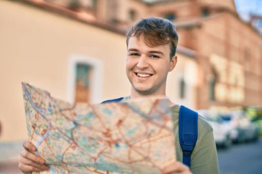 Kafkasyalı genç turist gülümseyerek şehirde haritayı tutuyor..