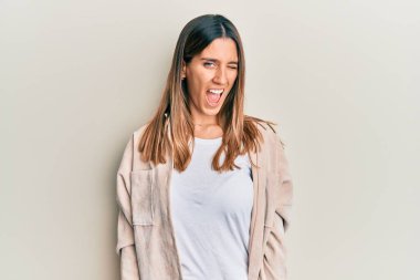 Esmer, sıradan kıyafetler giyen genç bir kadın kameraya seksi bir ifadeyle bakıyor, neşeli ve mutlu bir yüzle.. 