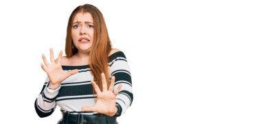 Genç, güzel, kızıl saçlı, zarif kıyafetler giyen, tiksindirici bir ifade takınan, tiksindirici, tiksindirici bir yüz ifadesi olan bir kadın. Eller havada. 