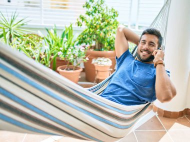 Genç İspanyol adam terasta hamakta uzanmış akıllı telefonda rahatça konuşuyordu..