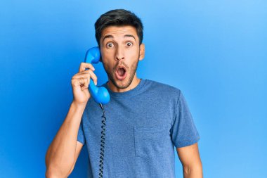 Bağbozumu telefonda konuşan genç yakışıklı adam korkmuş ve ağzı açık şaşkınlık içinde şaşırmış, inançsız yüz. 