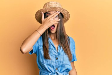 Genç İspanyol kadın yaz şapkası takıyor. Şoka giriyor. Yüzünü ve gözlerini eliyle kapatıyor. 
