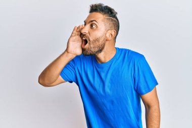 Sakallı, sıradan kıyafetler giyen, eli ağızda bağırıp çağıran yakışıklı bir adam. iletişim konsepti. 