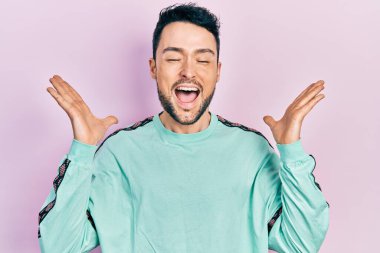 Gündelik kıyafetler giyen genç İspanyol adam başarı için deli ve çılgınlığı kutluyor kollarını kaldırmış ve gözlerini kapatmış heyecanla bağırıyor. Kazanan konsept 