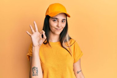 Teslimat üniforması giyen, şapkalı, gülümseyen genç İspanyol kadın el ve parmaklarıyla 
