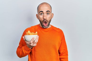 Genç kel adam elinde patates cipsi tutuyordu. Korkmuş ve şaşkına dönmüştü. Şaşırmak için ağzı açıktı. 