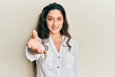 Güzel bir ortadoğulu kadın günlük kıyafetler giyip dostça bir şekilde el sıkışarak selamlıyor ve selamlıyor. başarılı iş. 