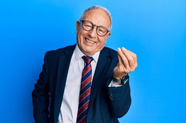 Beyaz üst düzey bir adam takım elbise ve kravat takıyor. İtalyan jesti yapıyor. Elleri ve parmakları kendinden emin. 